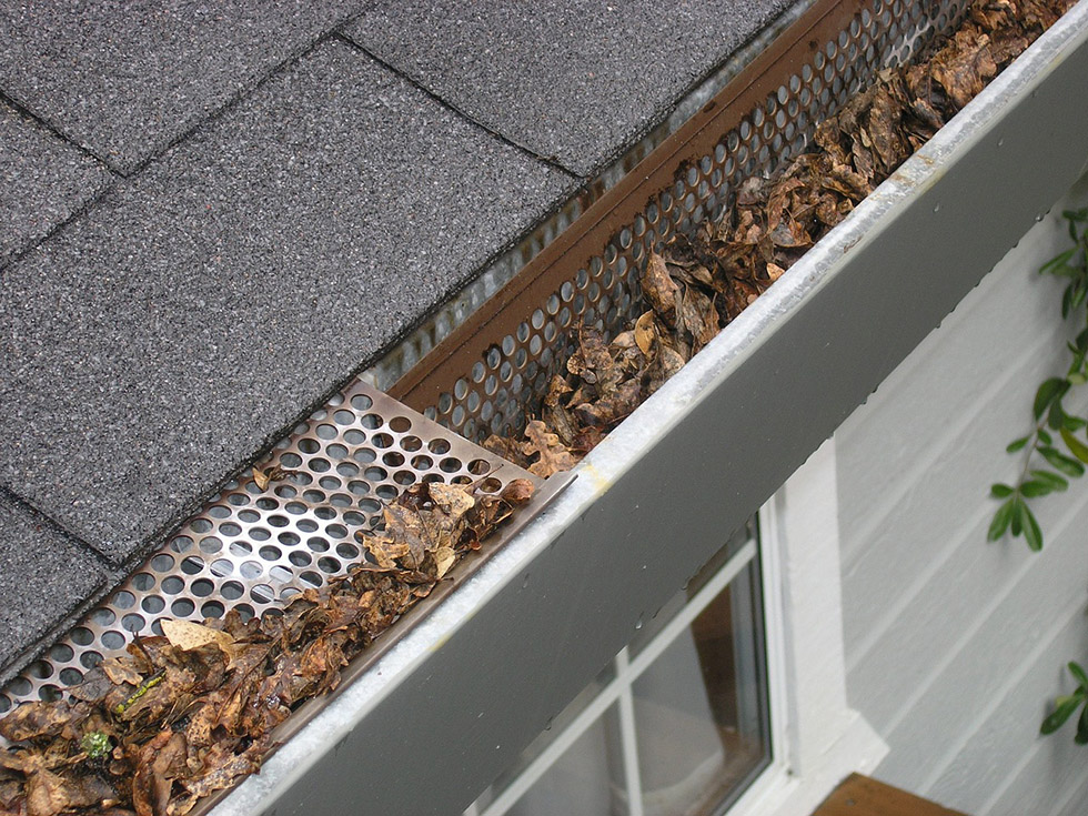 a home gutter clogged with leaves and debris