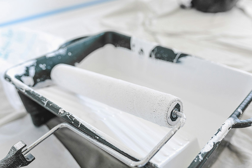 Paint roller in tray of white paint