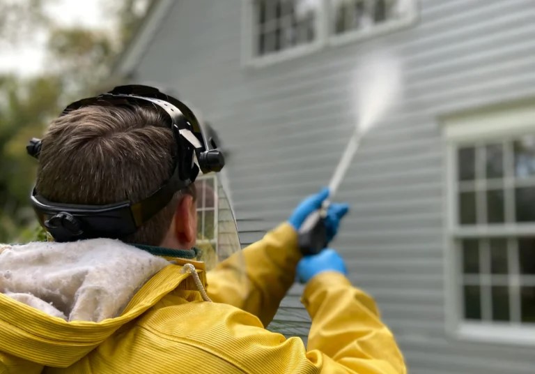 A residential pressure washing professional cleaning a house