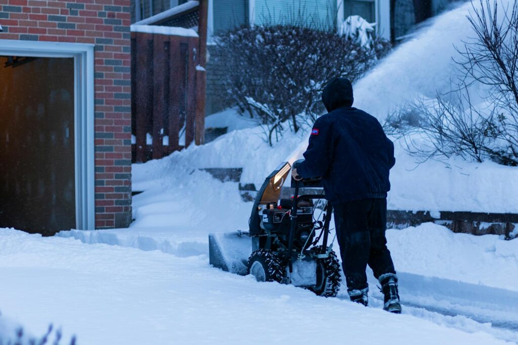 A homeowner clearing a path with a snow blower on his property
